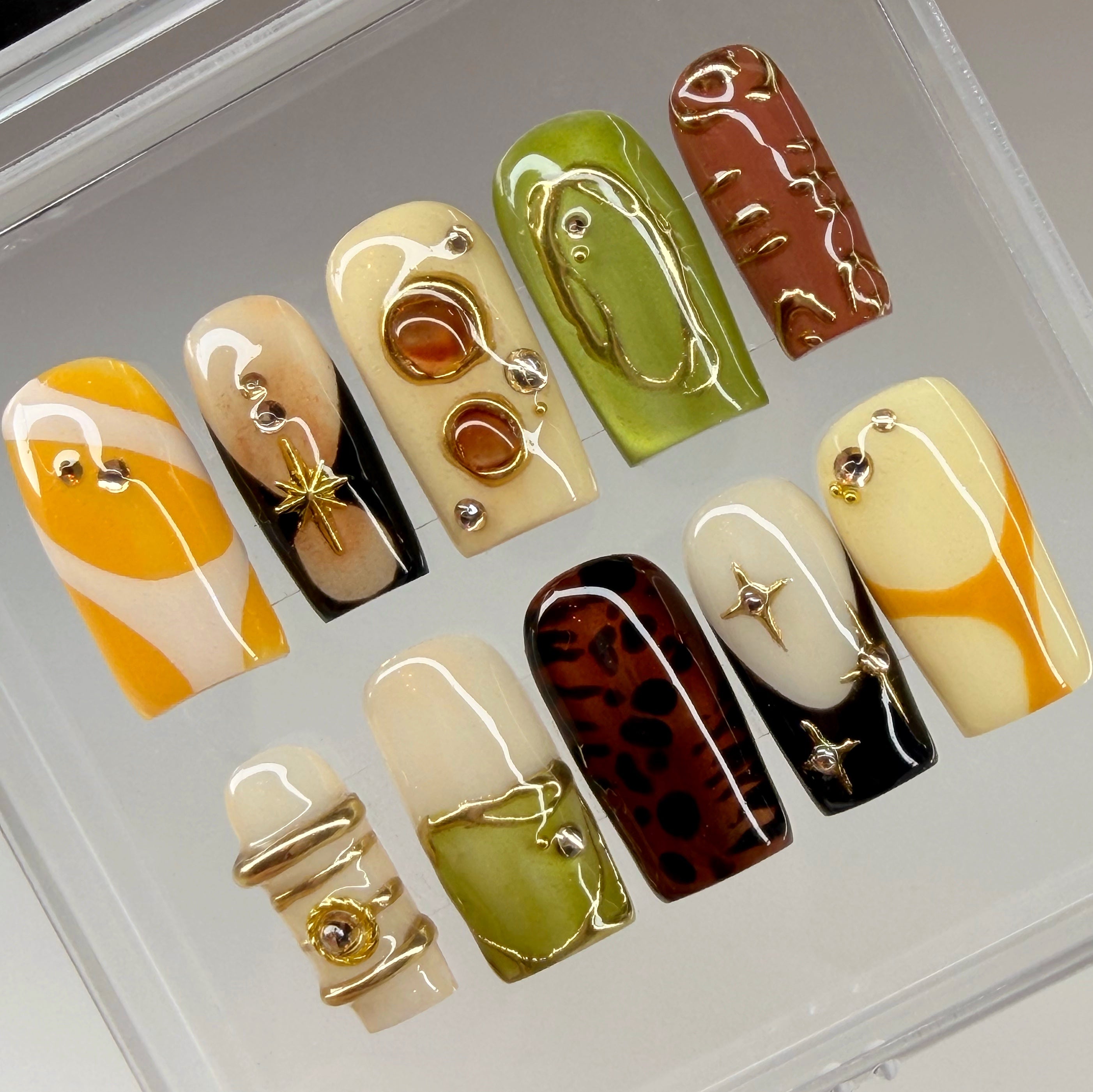 Set of decorative nail art with various patterns and yellow tone colors on a clear background