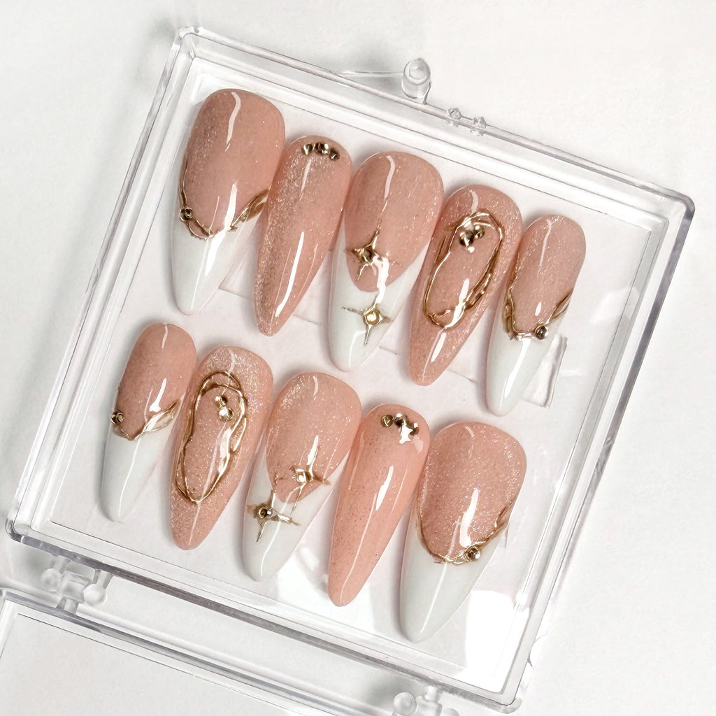 Set of nude, white and gold nail art designs in a clear case on a white background