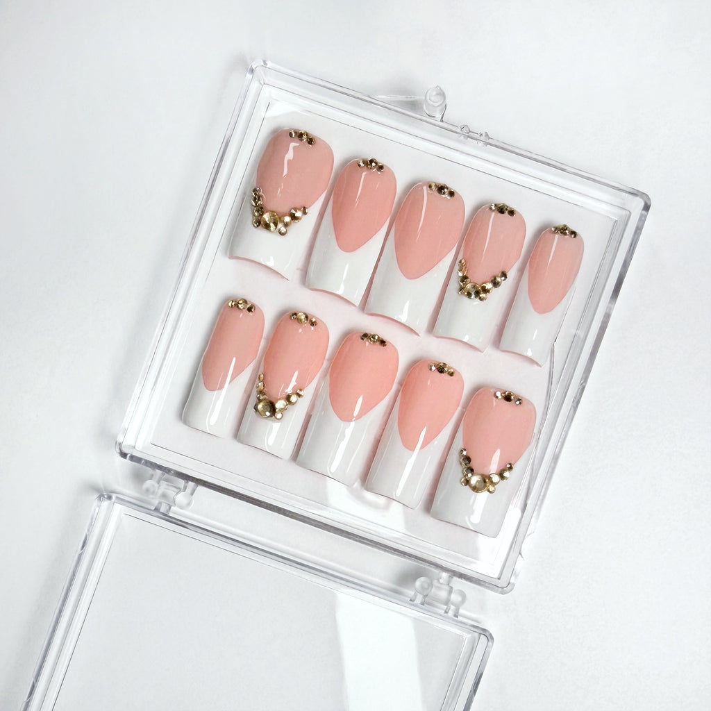 Set of pink and white with gold decorative nails in a clear case on a white background