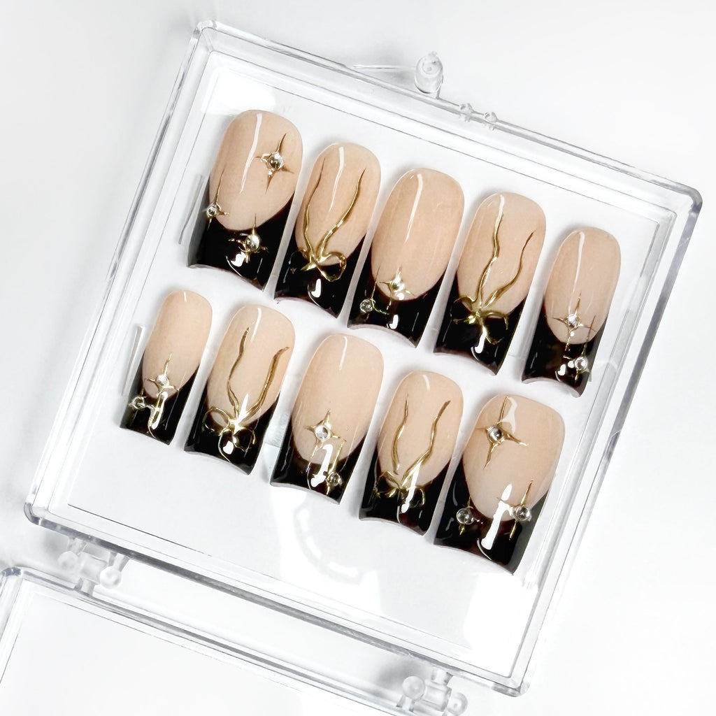 Set of beige and black nail art designs in a clear case on a white background