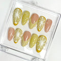 Set of press-on nails with lemon and yellow design in a clear case on a white background