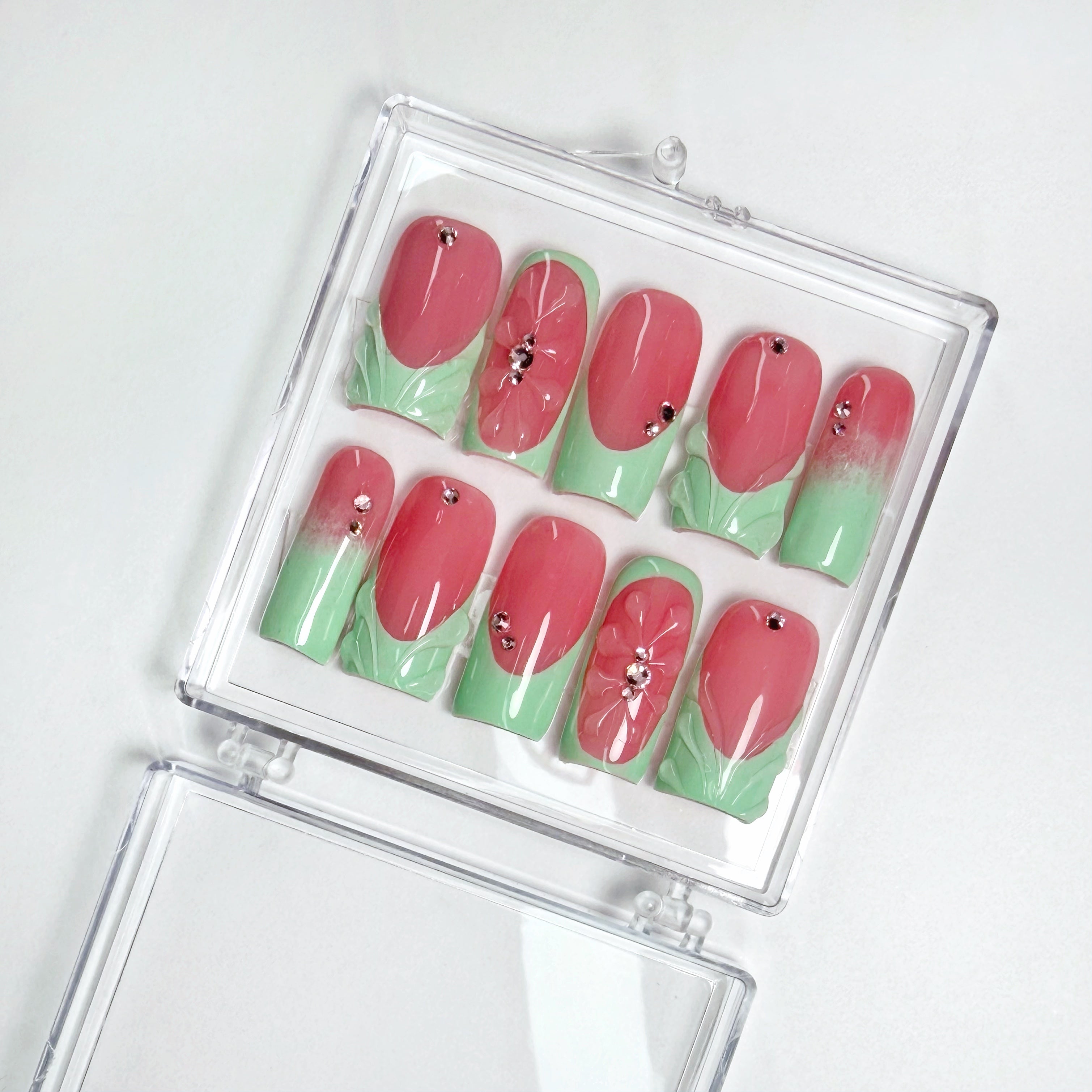 Set of pink and green guava-themed nail art designs in a clear case on a white background