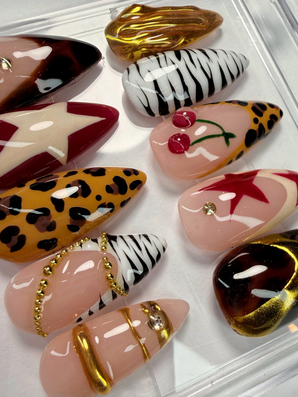 Collection of decorative false nails with various patterns and designs on a white background.