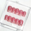 Set of pink glittery nails with gold accents in a clear case on a white background