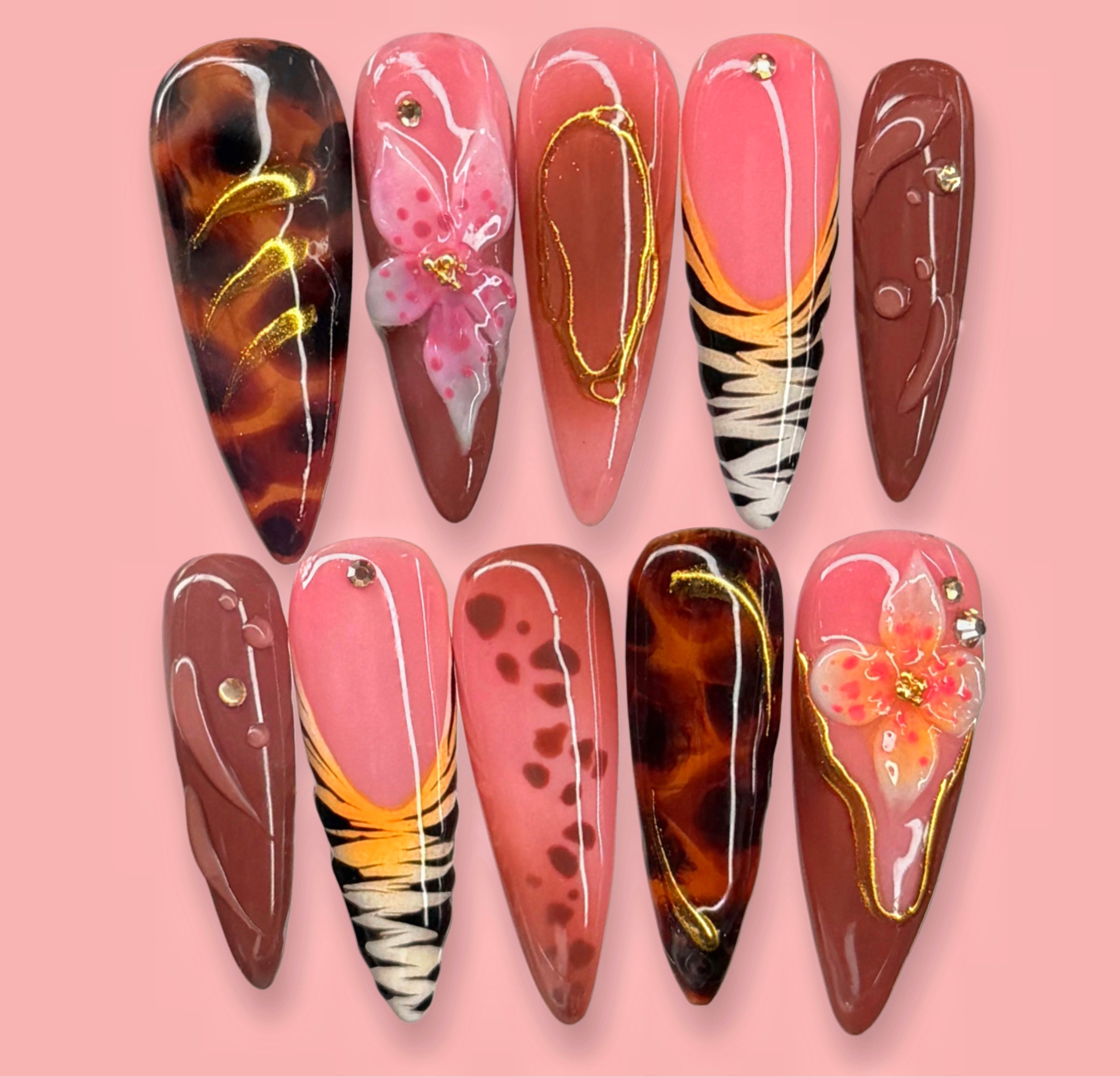 Pink and brown handmade press-on nail set with tortoiseshell, floral, and gold accent designs on a pink background.