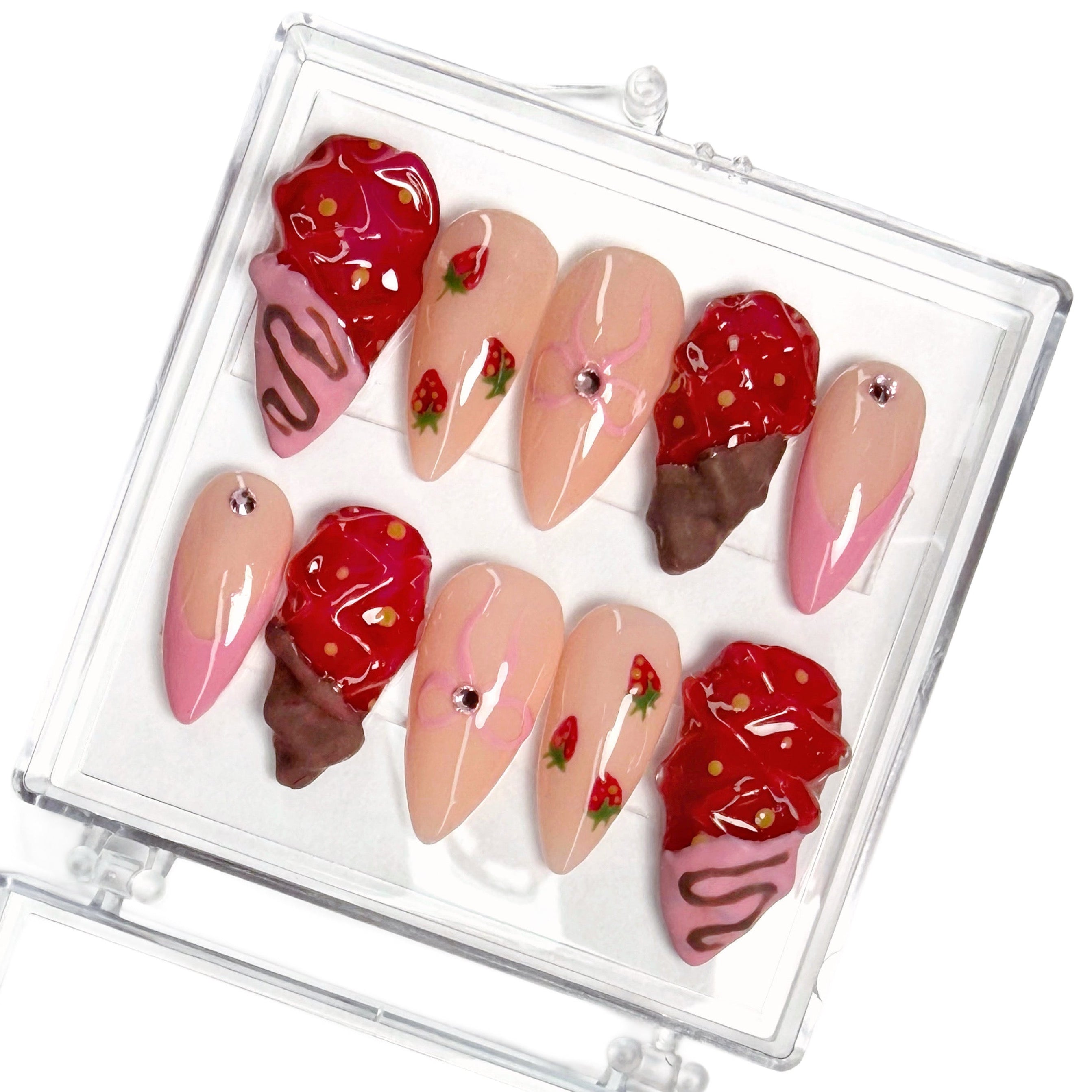 Set of decorative nail art with chocolate dipped strawberry and bow designs in a clear case.