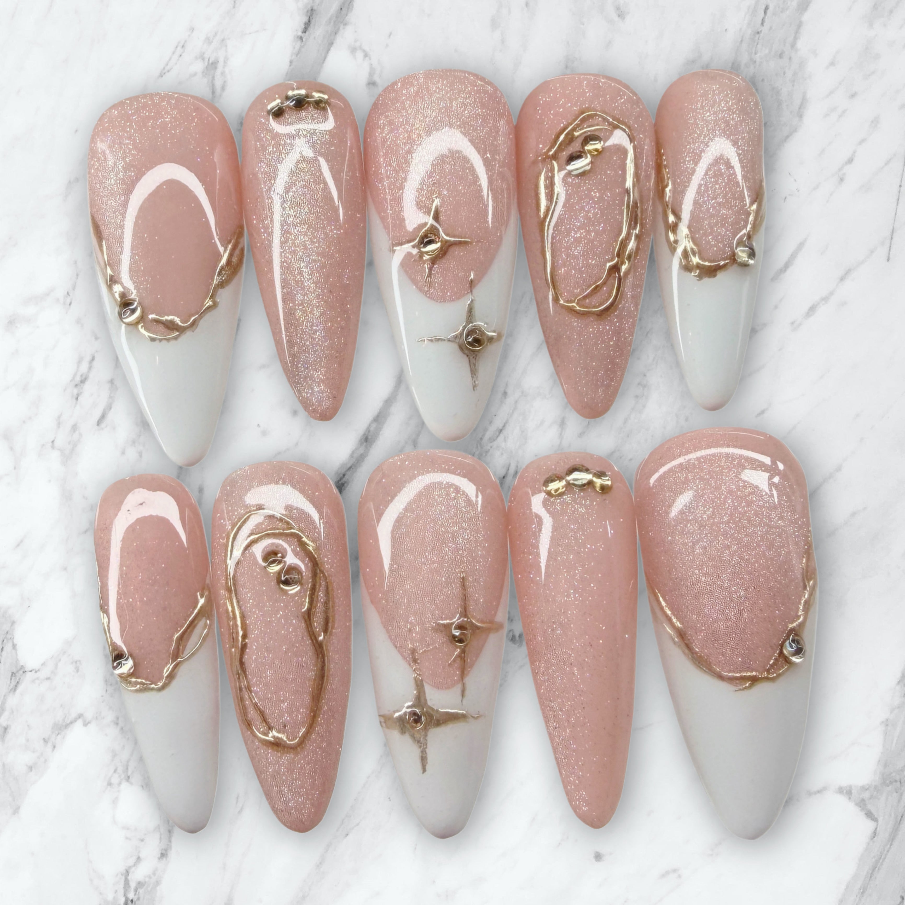 Nail art with pink and gold designs on a marble background