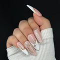 Hand with pink and white nails featuring gold accents against a black background