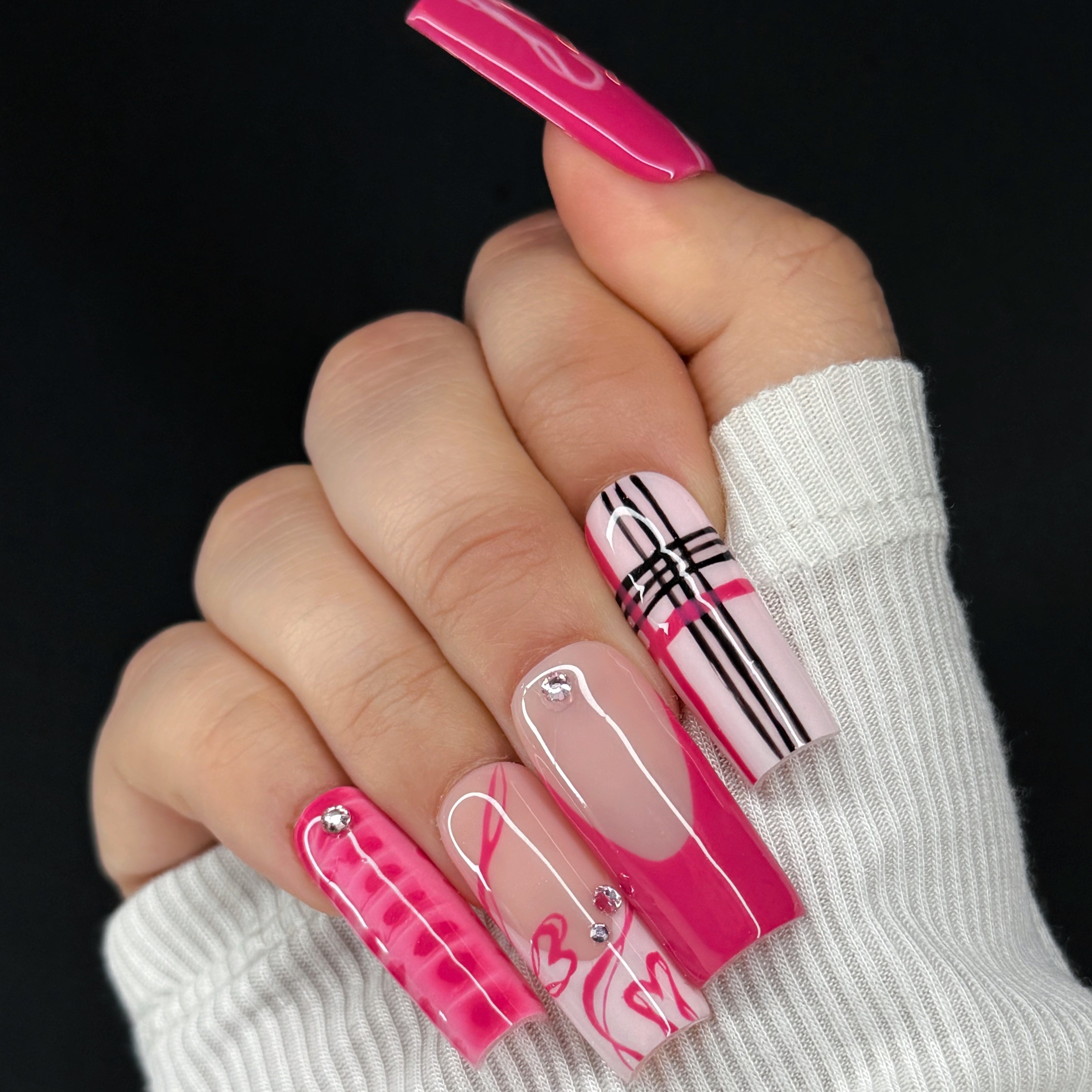 Hand with pink and white checkered nail design on a black background