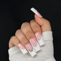 Hand with pink and white nail polish on a black background