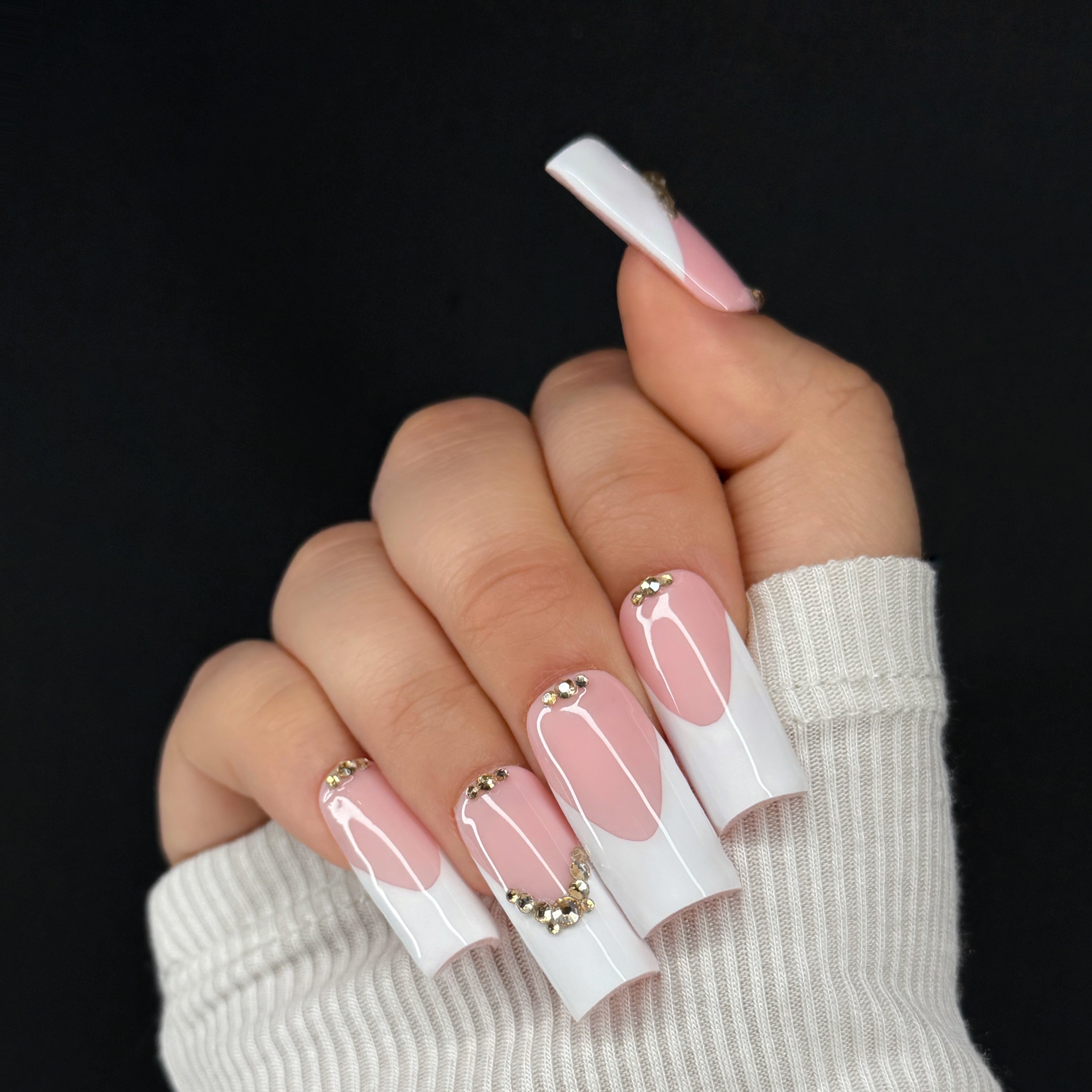 Hand with pink and white nail polish on a black background