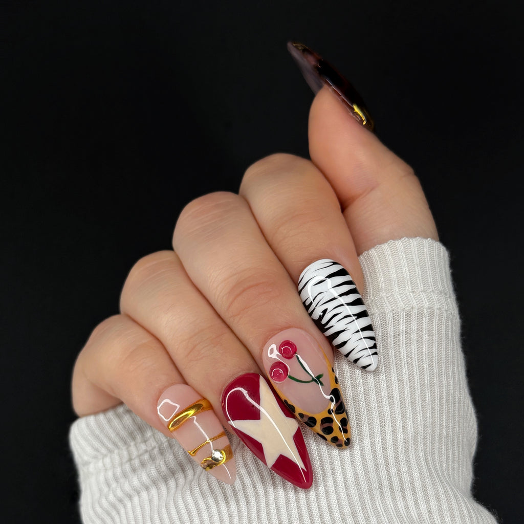Hand with intricately designed nails featuring various patterns on a black background