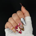 Hand with intricately designed nails featuring various patterns on a black background